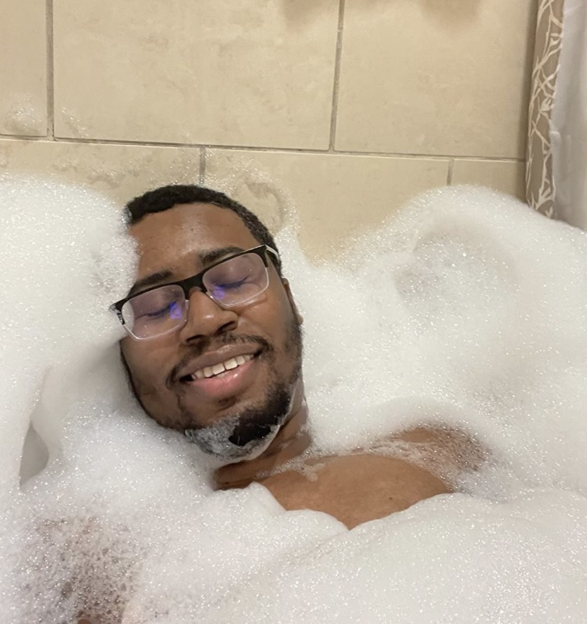 A person taking a bath with lots of bubbles