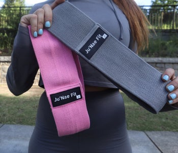 model holds up thick pink and gray resistance bands