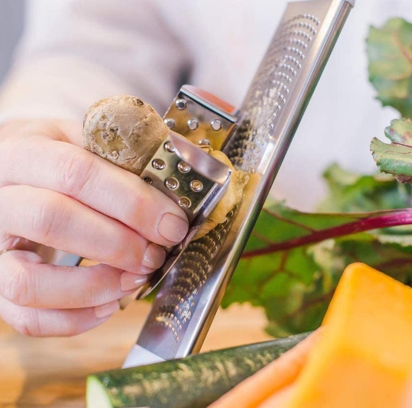 a person grating ginger while using the hand guard 