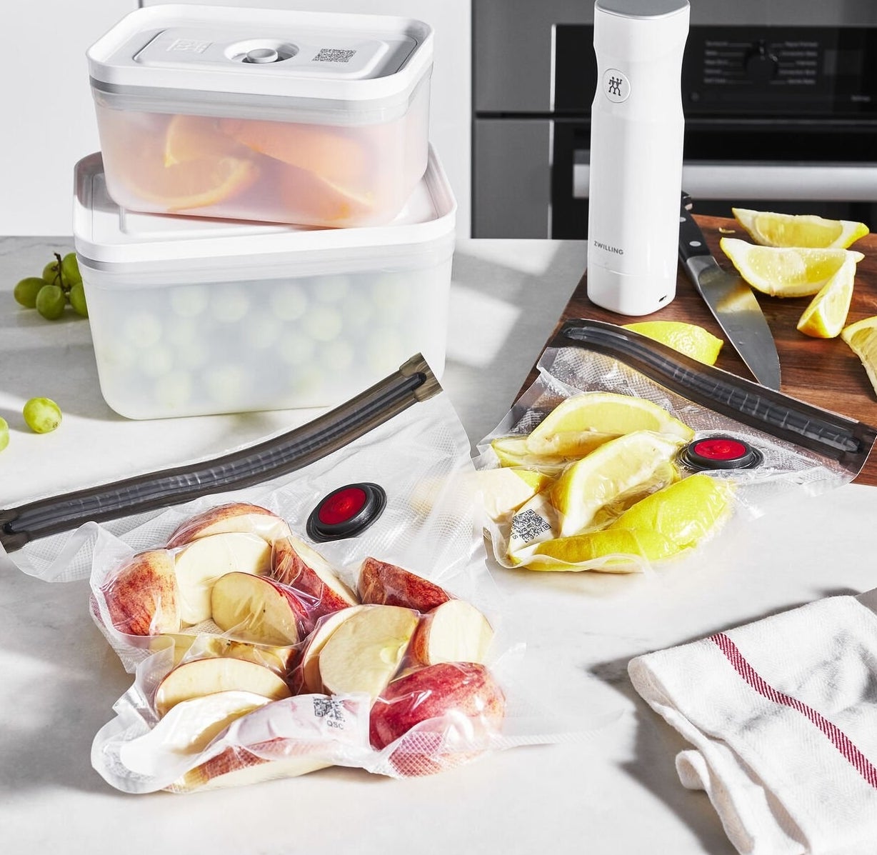 the vacuum sealer, two containers filled with fruit, and bag filled with apples and lemons 