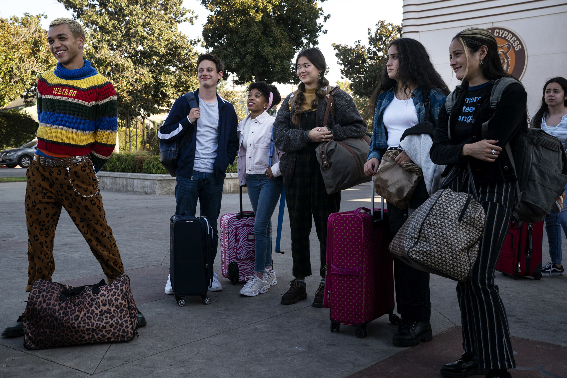 Students prepare to get on a school bus with their luggage and bags. 