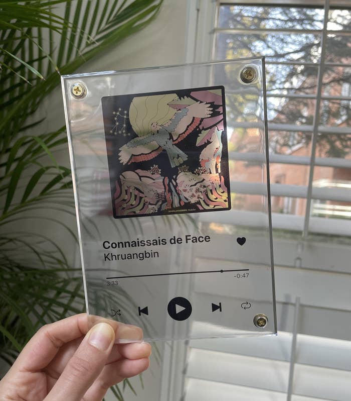 Brittany holding up a song plaque with Khruangbin&#x27;s album Mordechai on it, showing the song Connaissais de Face 