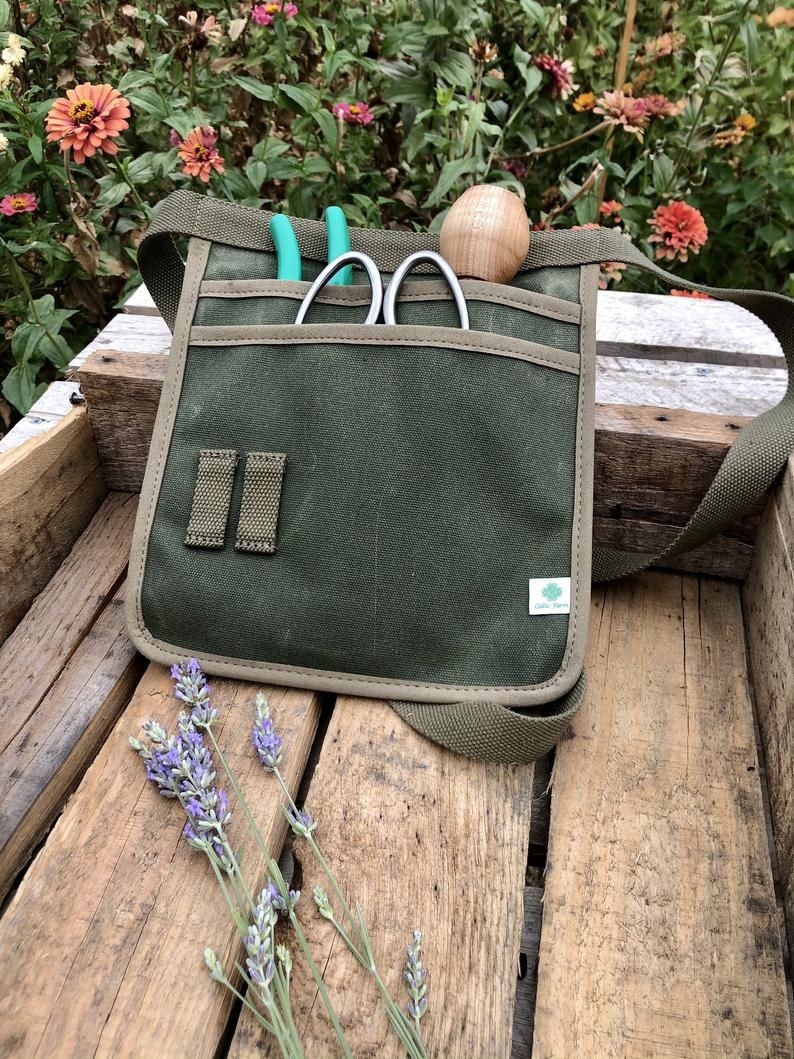 Green belted pouch with two deep pockets full of gardening tools 