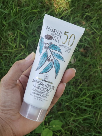 hand holding the bottle of sunscreen 