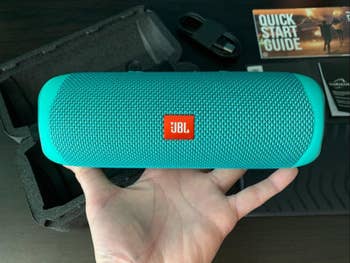 different reviewer holding a teal speaker