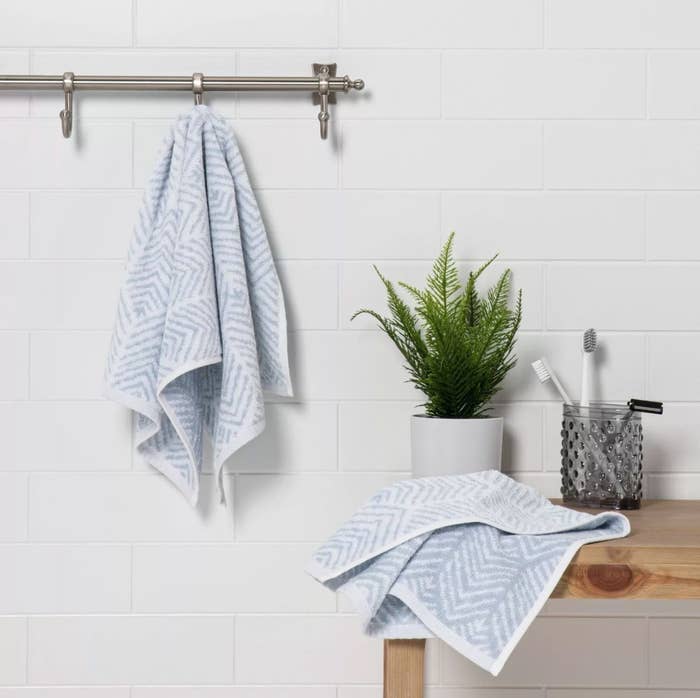 The two-pack of chevron hand towels in light blue in a bathroom