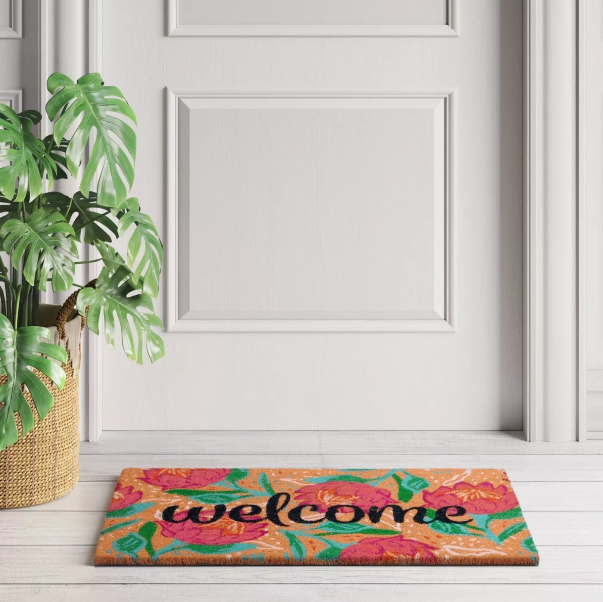 The &#x27;welcome&#x27; doormat in black lettering with a floral background on a doorstep
