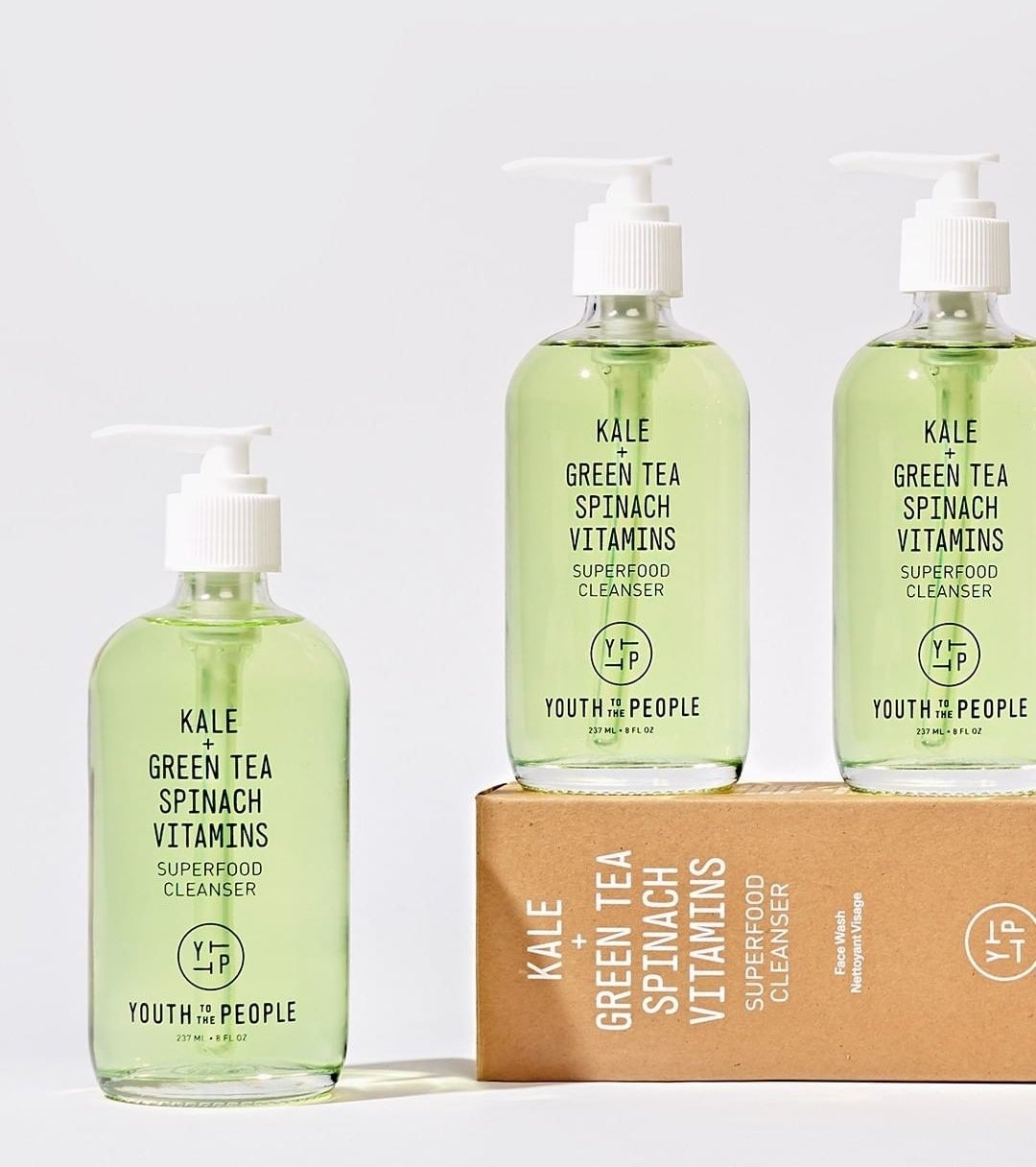 A trio of facial cleansers in transparent glass bottles arranged on a simple background