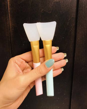 reviewer holding two silicone brushes