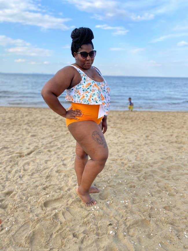A reviewer in the solid orange high-waist bottoms and white (with green and orange floral) top