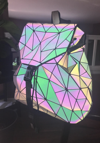 the backpack looking luminous in pastel colors when it's in the dark and light is reflected on it