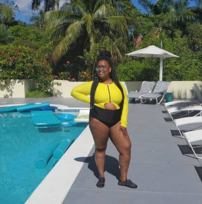 A reviewer in the yellow and black long sleeve swimsuit with a semi-circle cutout at the waist