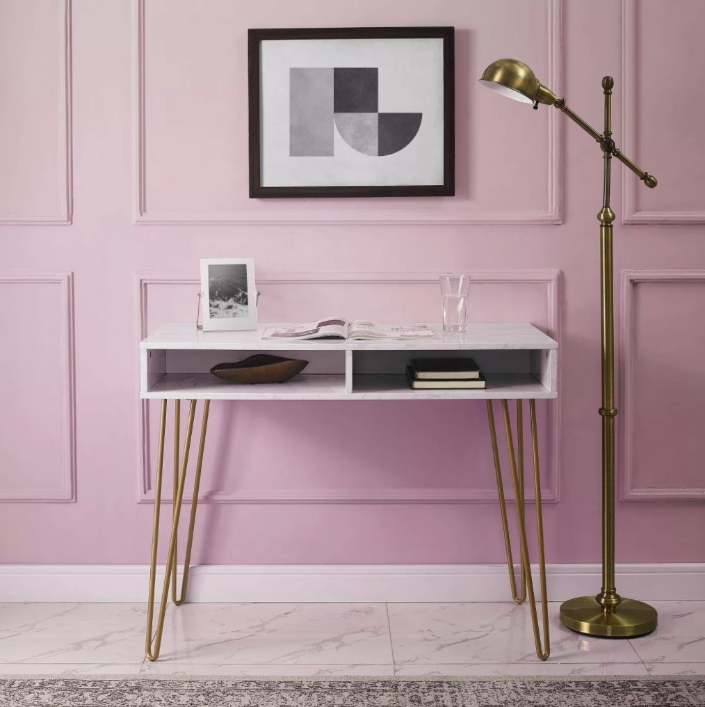 The desk against a pink wall with a magazine on top