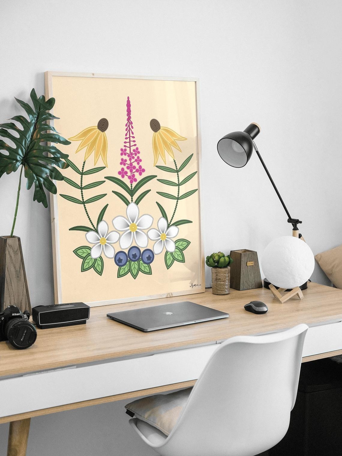 A symmetrical image of flowers and flora framed and sitting on a desk 