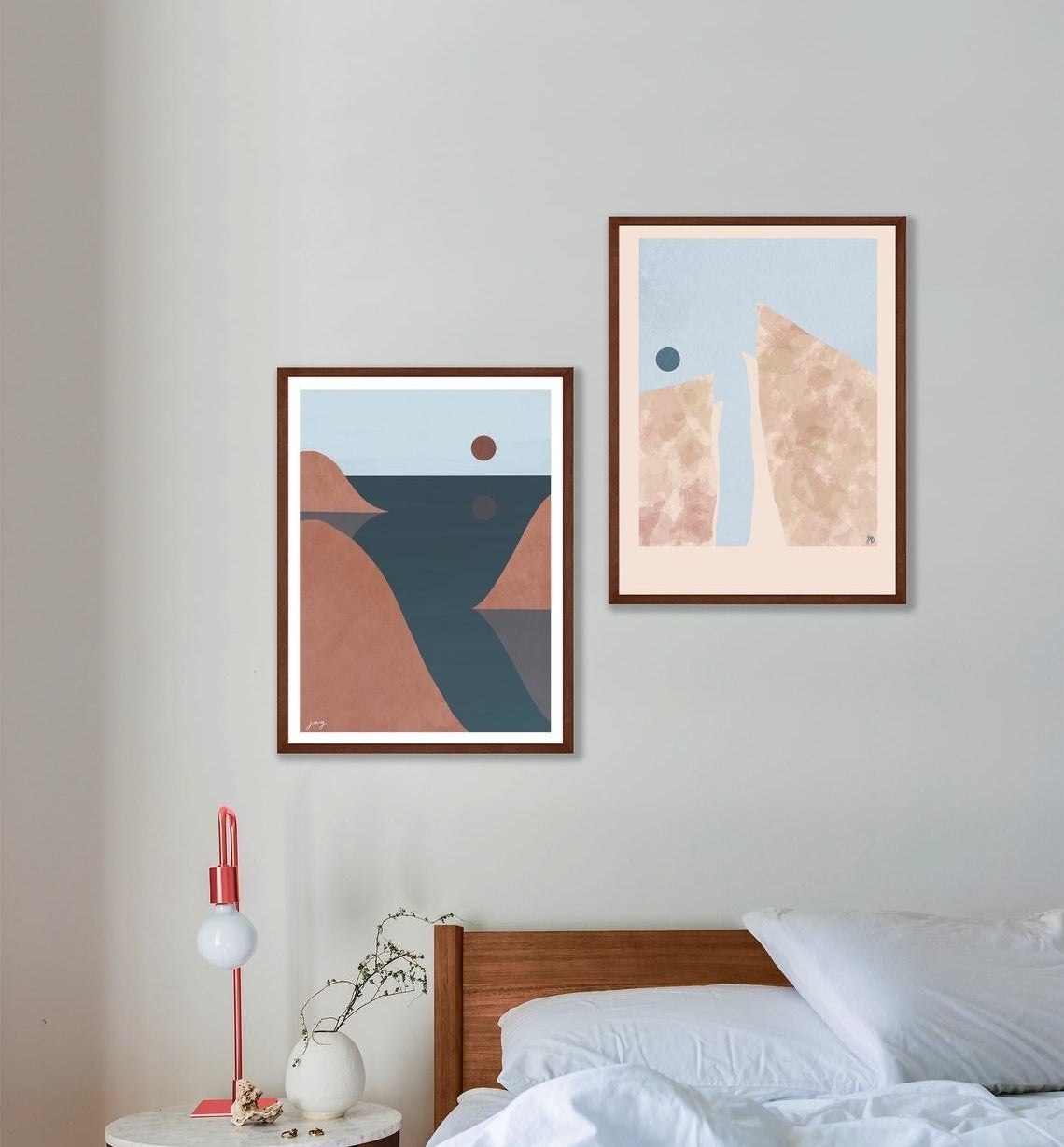 The pair of prints framed on a wall above a bed 