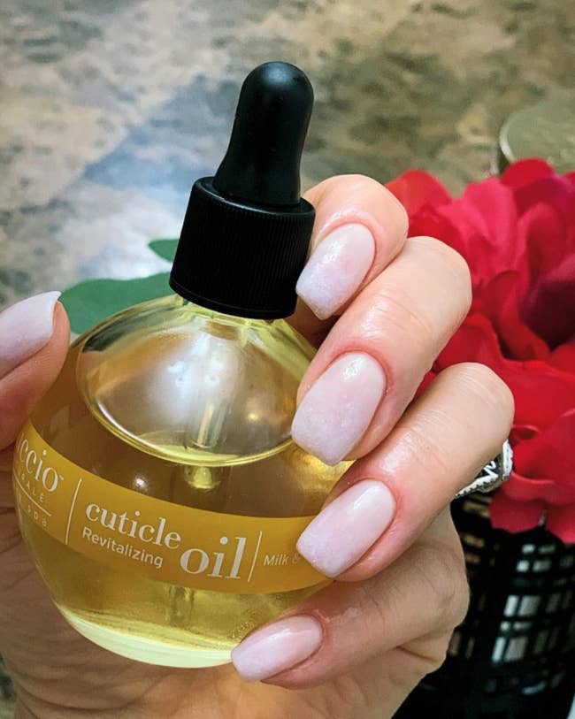reviewer holding jar of oil with healthy looking nails and cuticles