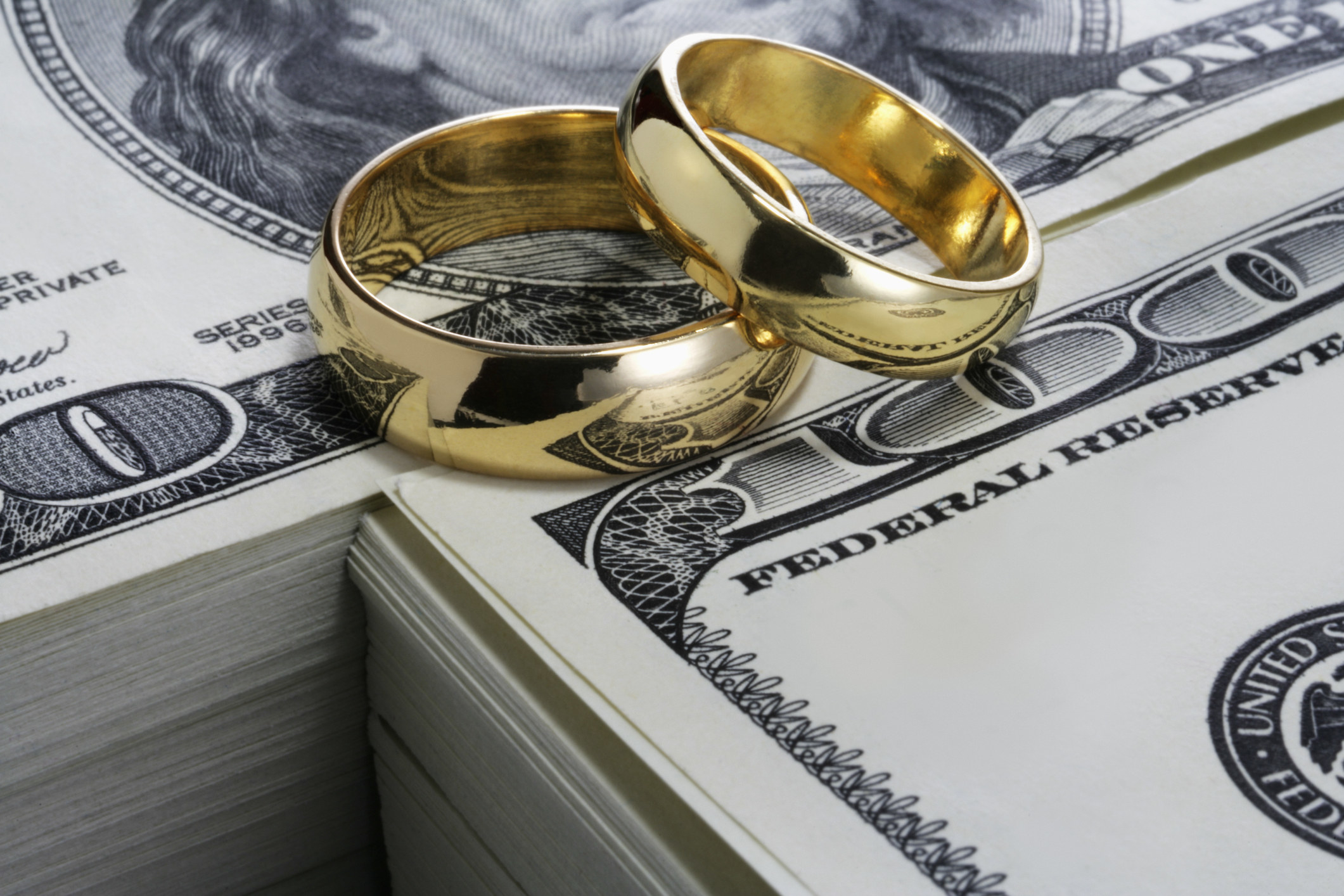 Wedding rings on stacks of hundred dollar bills