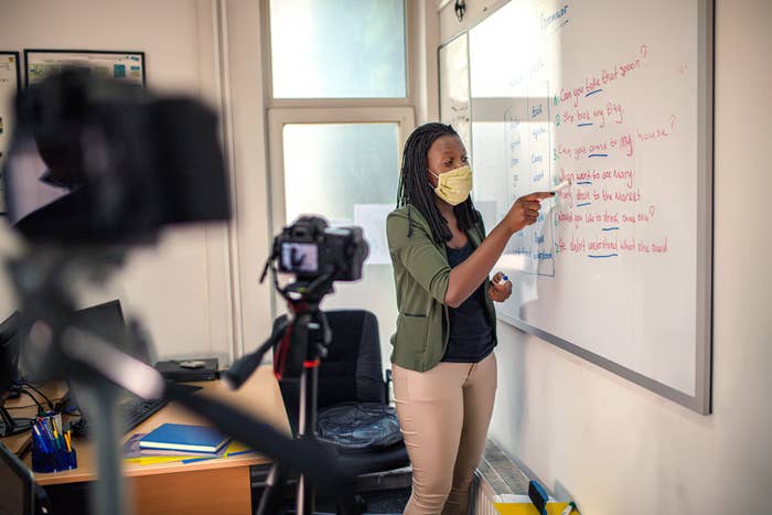  A teacher standing near a whiteboard and filming a digital lesson