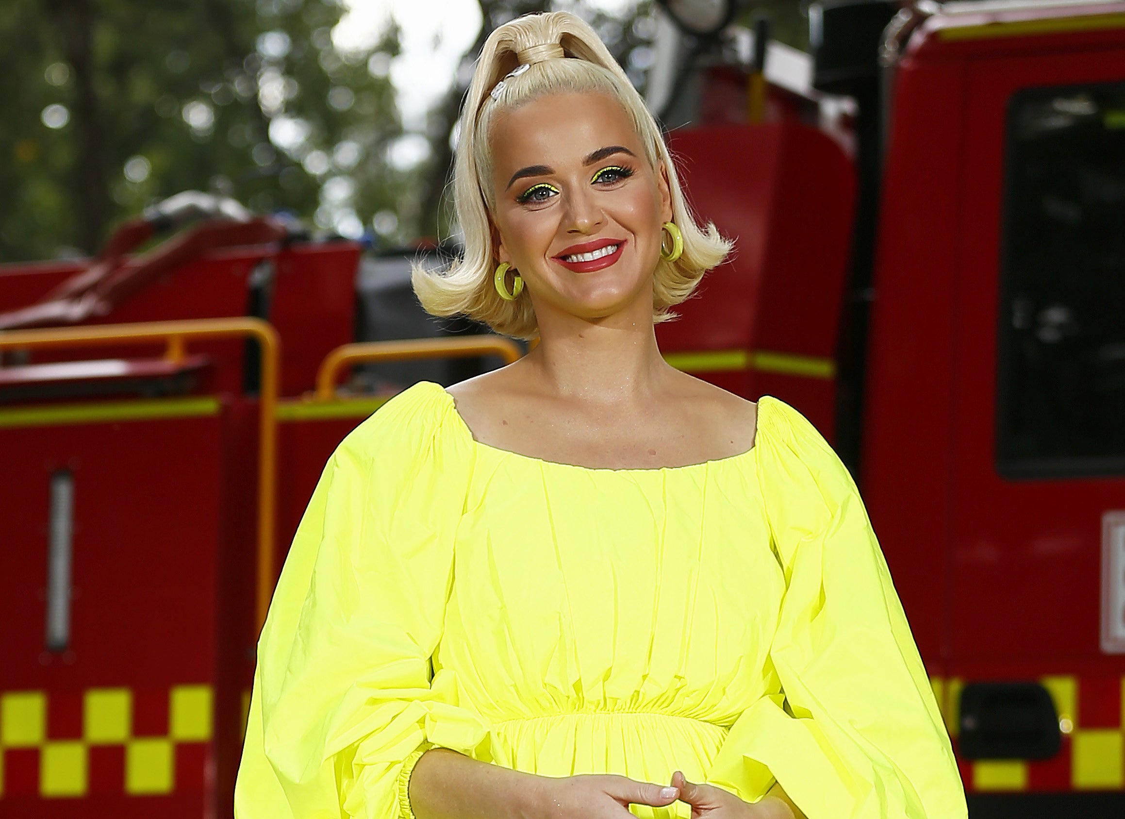 Katy smiles in a brihgt yellow dress