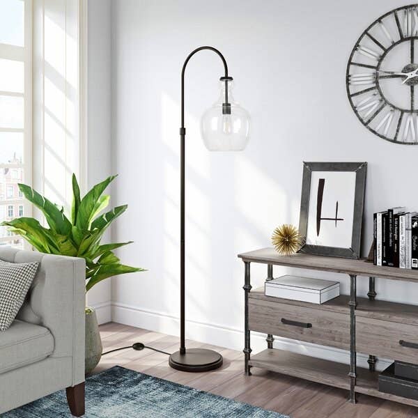 black arched lamp with circular base and round clear lampshade, in a living room