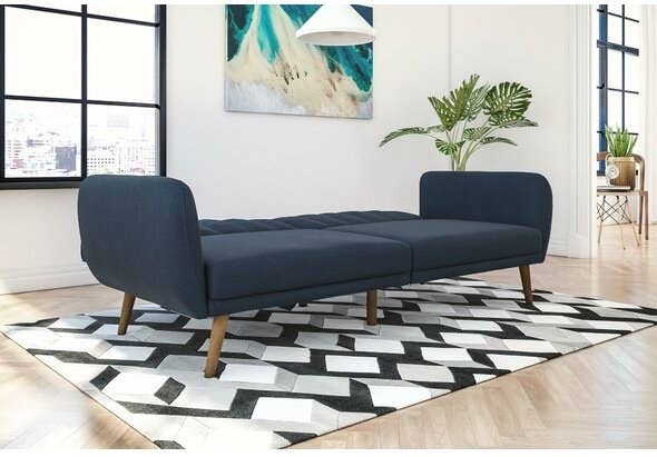 Navy blue sofa converted into a bed sitting in a living room on a black and white rug