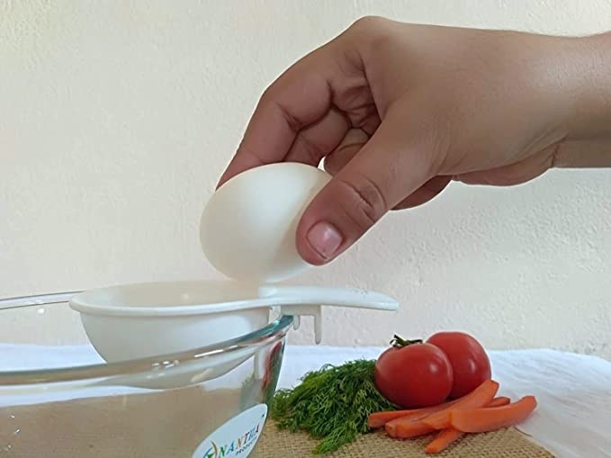 Person breaking an egg into a bowl with the yolk separator.