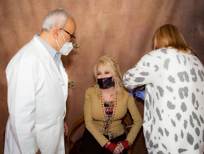 Dolly receives an injection from a nurse while wearing a mask
