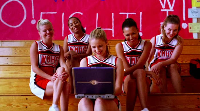 Quinn, Santana, and the other cheerleaders laughing at a video of Rachel Berry in Glee