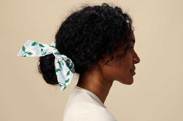 a model with a bow scrunchie around a low bun with a white and blue hydrangea print on it
