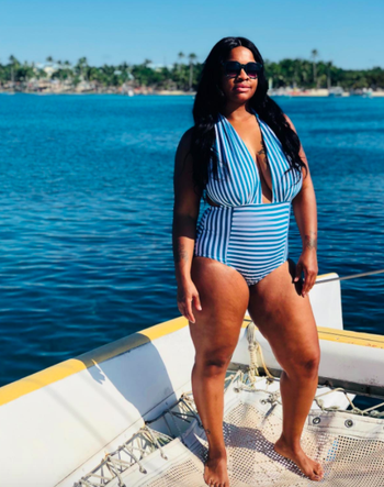 Reviewer in a blue and white striped plunge neckline one piece 