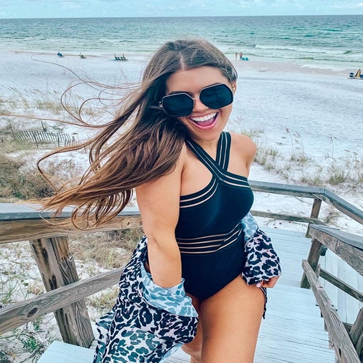 A model in the black swimsuit with black and mesh stripe waistband and crossover shoulder straps