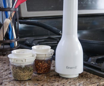 a reviewer photo of the white spice grinder and two pods filled with spices 