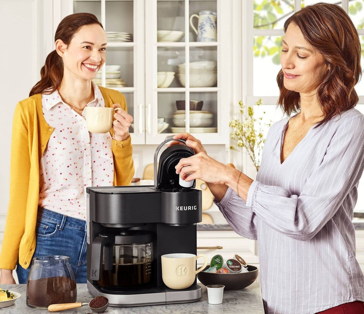 Two models in a kitchen around a Keurig coffee maker