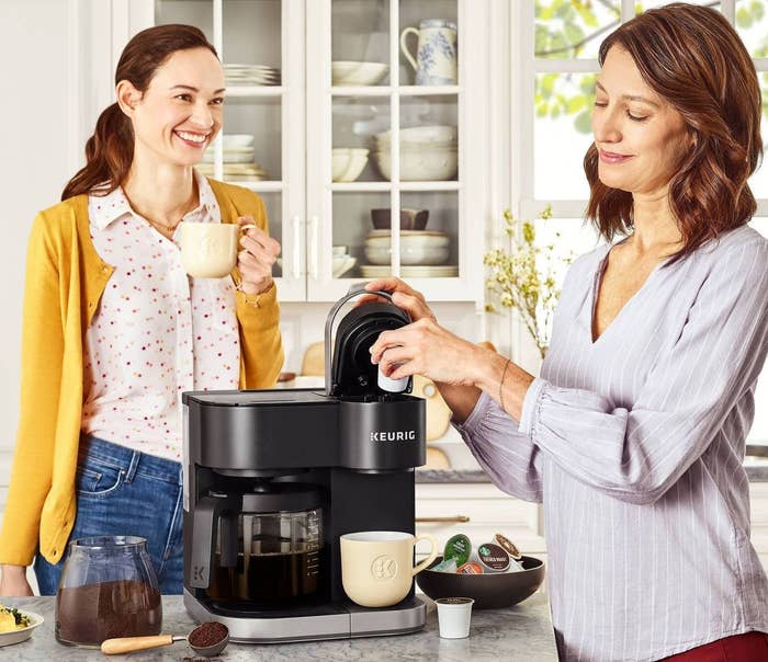 Two models in a kitchen around a Keurig coffee maker