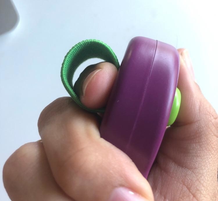 a reviewer holding the purple clicker which has a green finger band