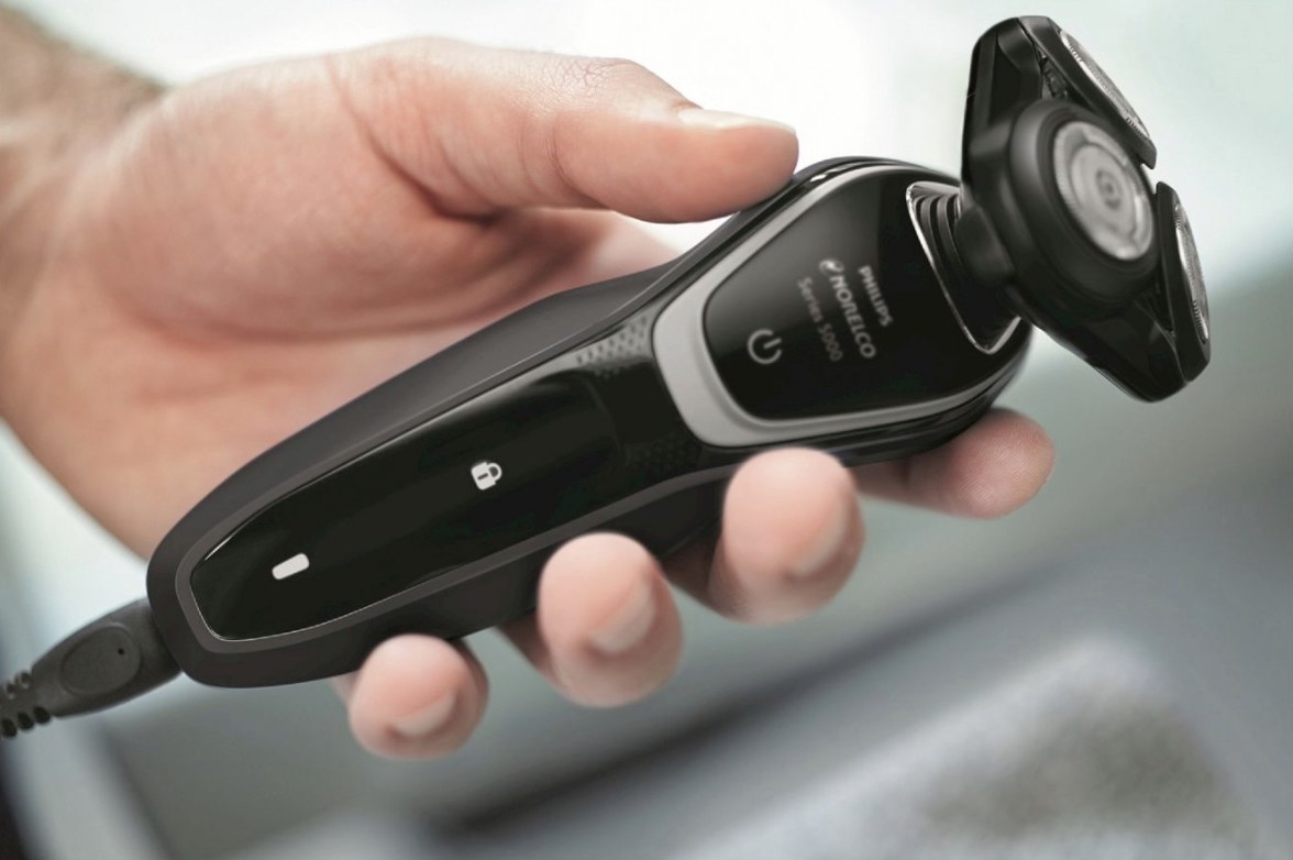 A black rechargeable electric shaver in a man&#x27;s hand