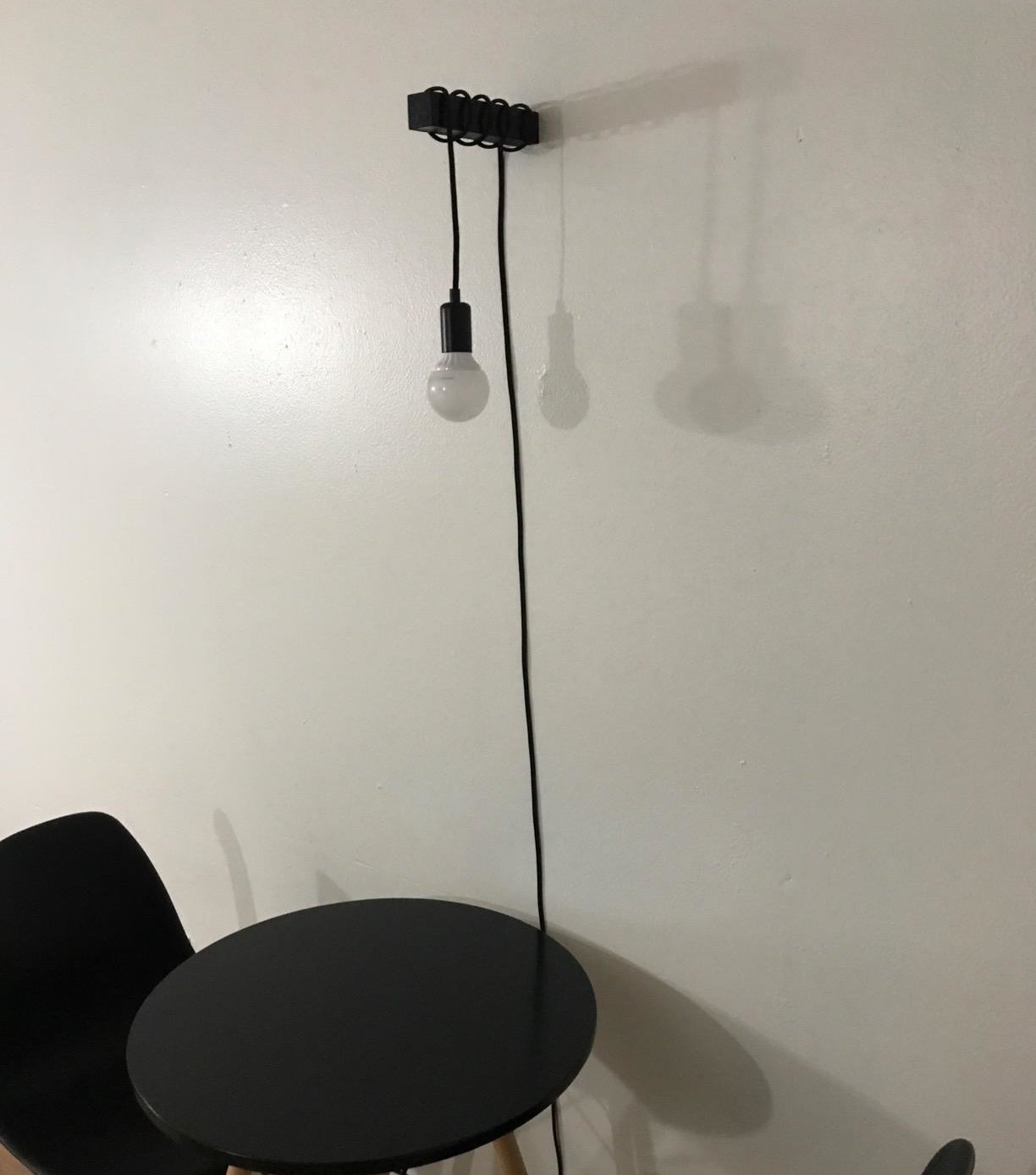 reviewer photo showing the edison bulb hanging above a small dining table