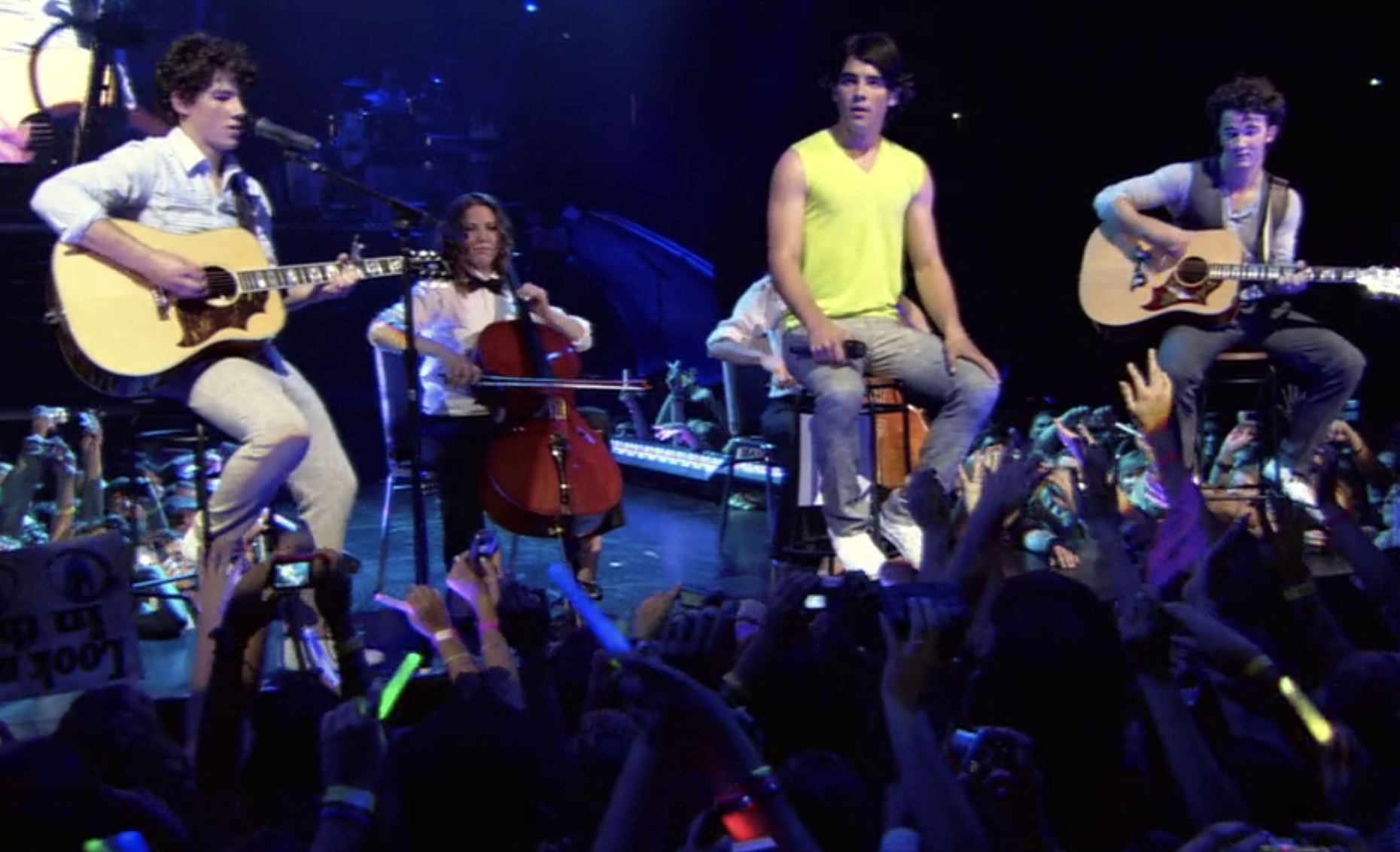 The Jonas Brothers sit down to perform a song as the crowd cheers them on