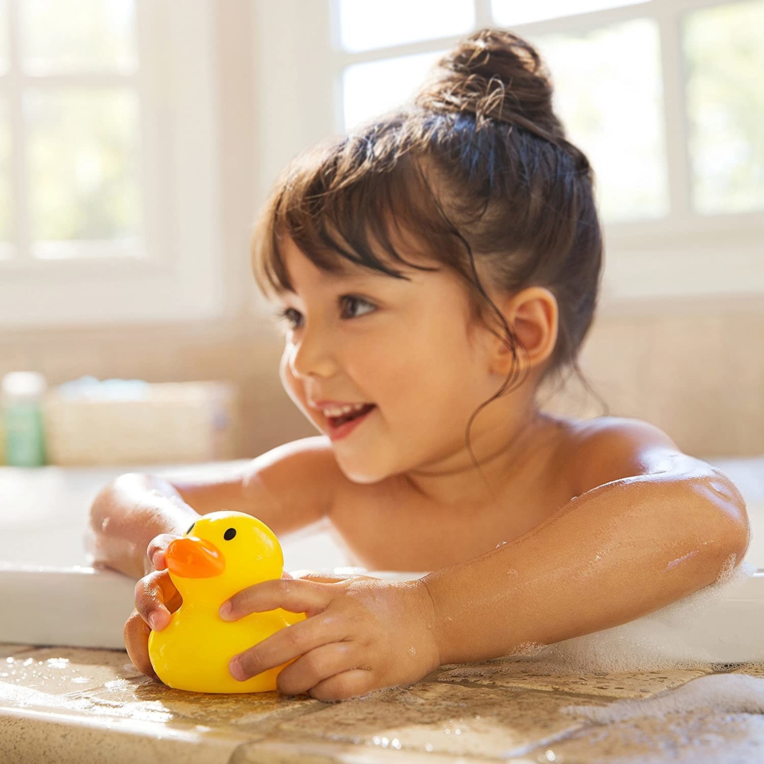 A kid holding the ducky in a bath