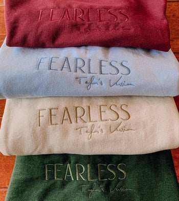 a stack of embroidered sweatshirts that say 