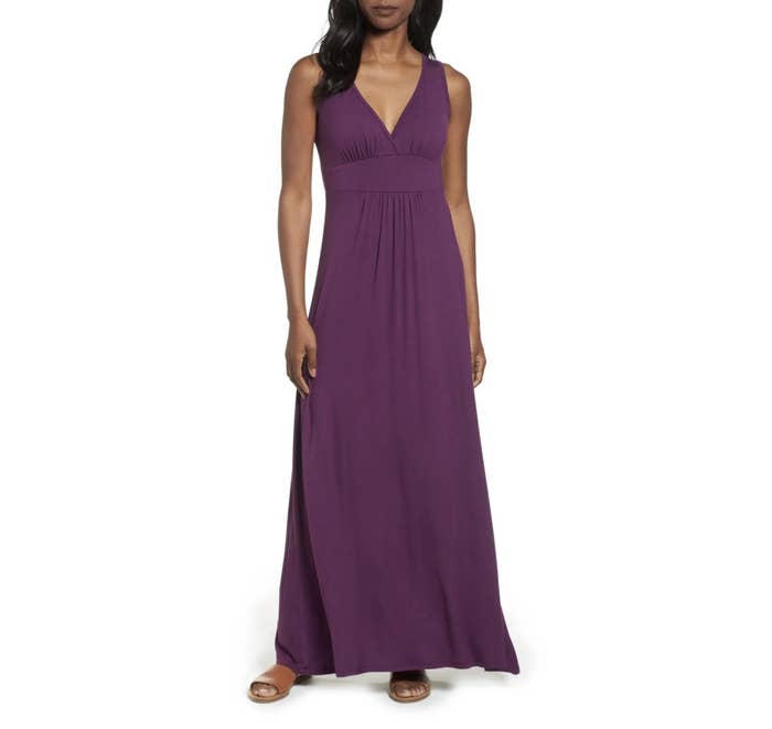 Model is wearing a purple maxi dress and sandals