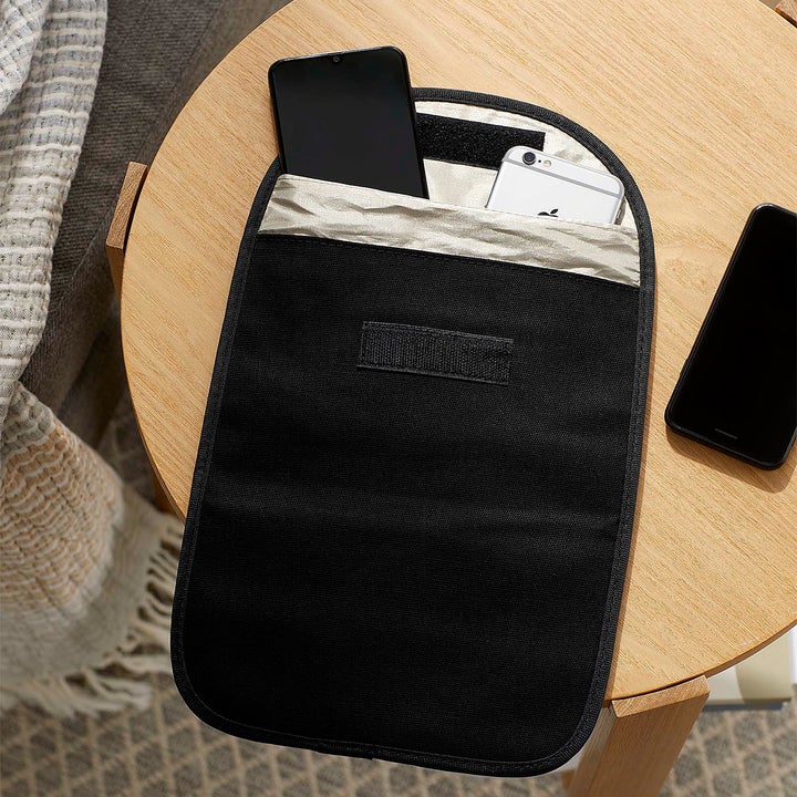 A flatlay of the clutch with three cell phones peeking out