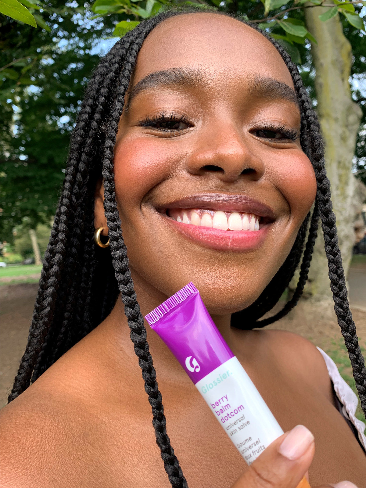 a smiling model holds up the berry balm dotcom tube