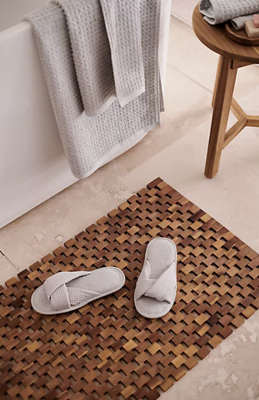 The gray criss cross slippers on a bath mat
