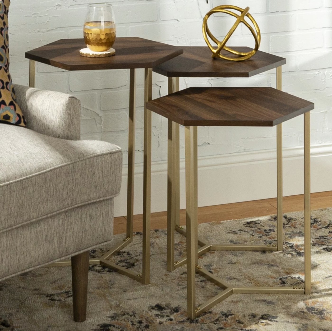 The nesting table in dark walnut/ gold holding a drinking glass and gold statue