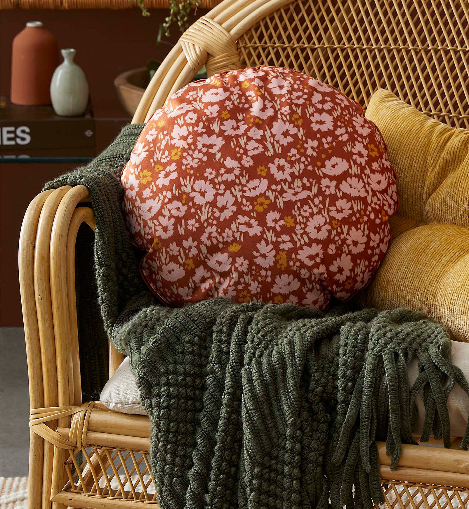 A round floral-print cushion on a wicker couch 