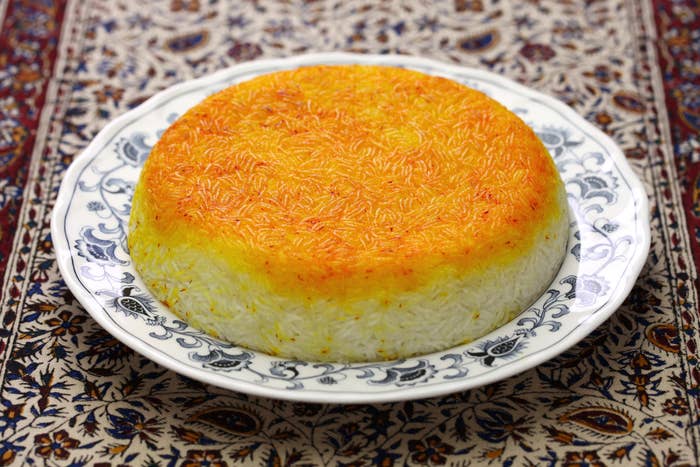 A perfectly smooth mound of rice, browned on the top, on a floral plate which sits on a patterned tablecloth