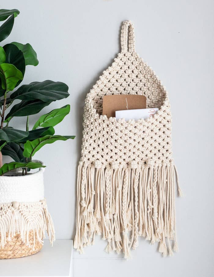 the cream-colored macrame envelope holder holding a few cards