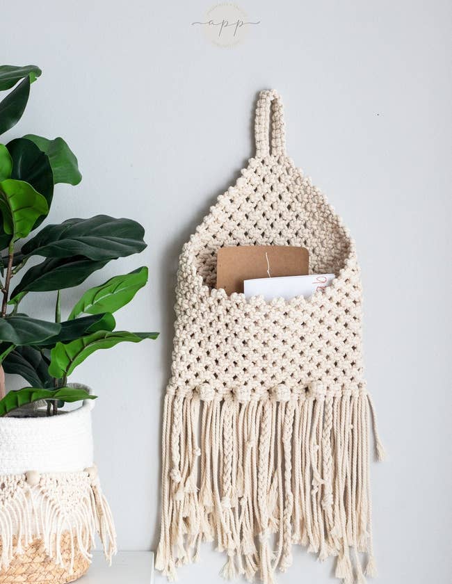the cream-colored macrame envelope holder holding a few cards