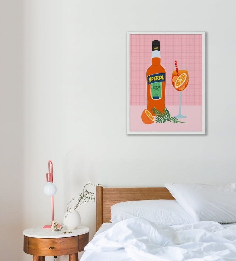 the pink Aperol poster hanging over a bed